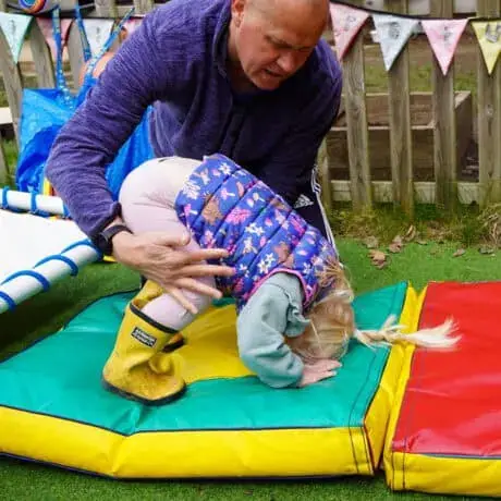 Staff supporting child learning to roll Staff supporting child learning to roll
