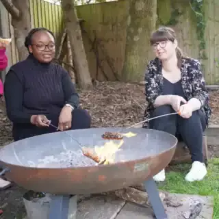 Nursery team cooking sausages on firepit Nursery team cooking sausages on firepit